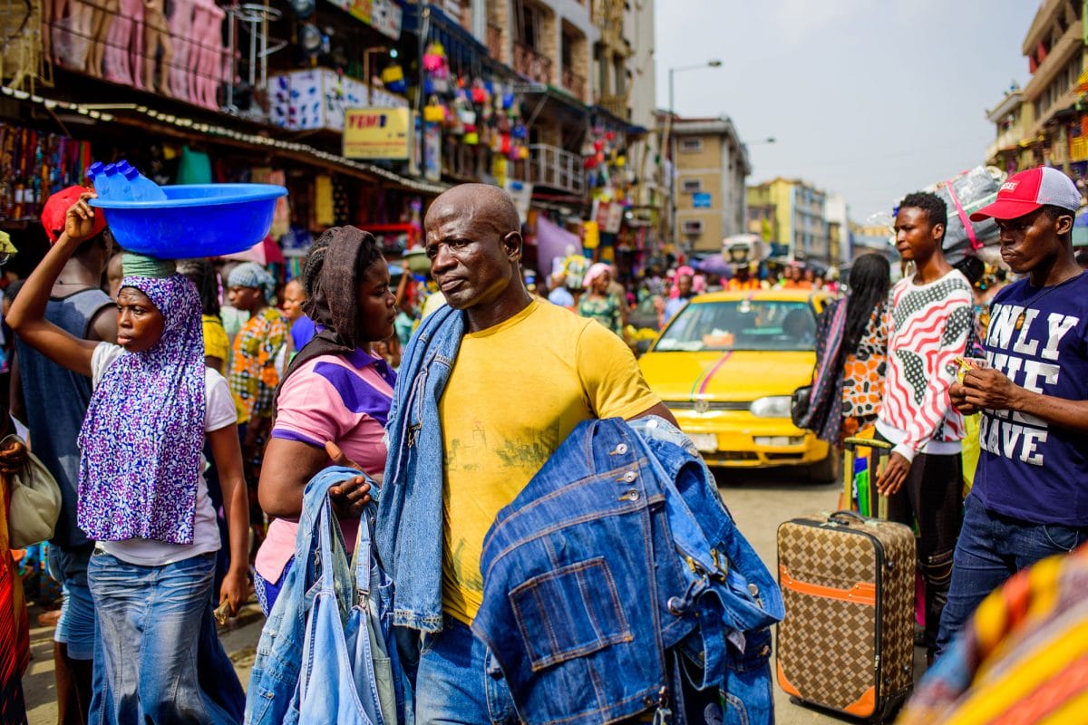 busy market street with man in yellow shirt carrying demin