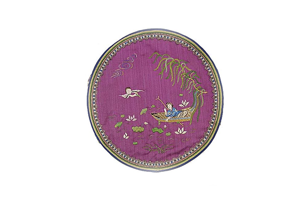 embroidered purple circle with bird flying towards girl in a small boat