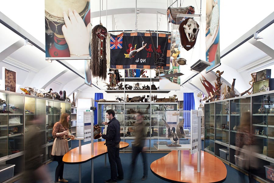 Several people walking in room with flags on ceiling and items against the wall