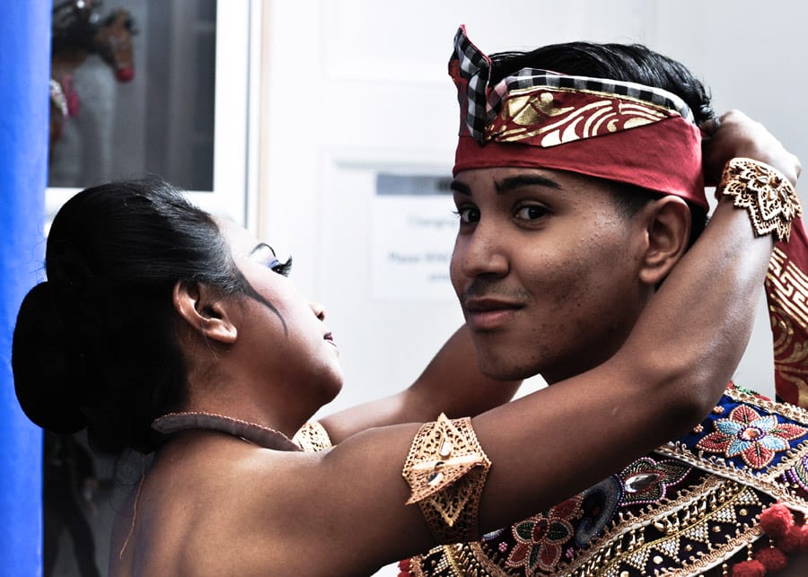 Woman putting head scarf on teenager.