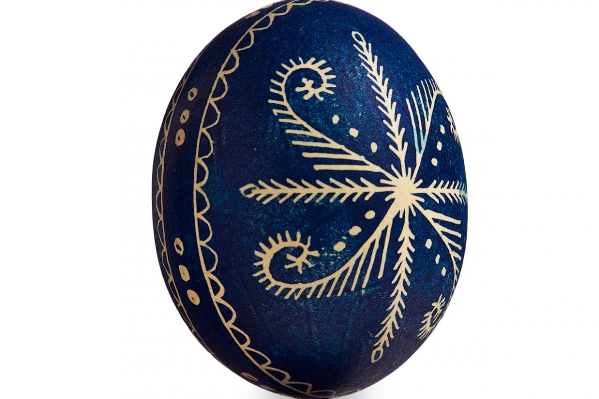 Blue egg with design carved into it that looks like a flower.