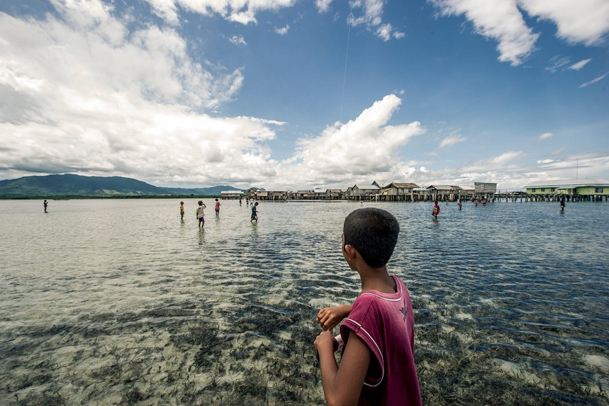 Boy looking at other children in the river.