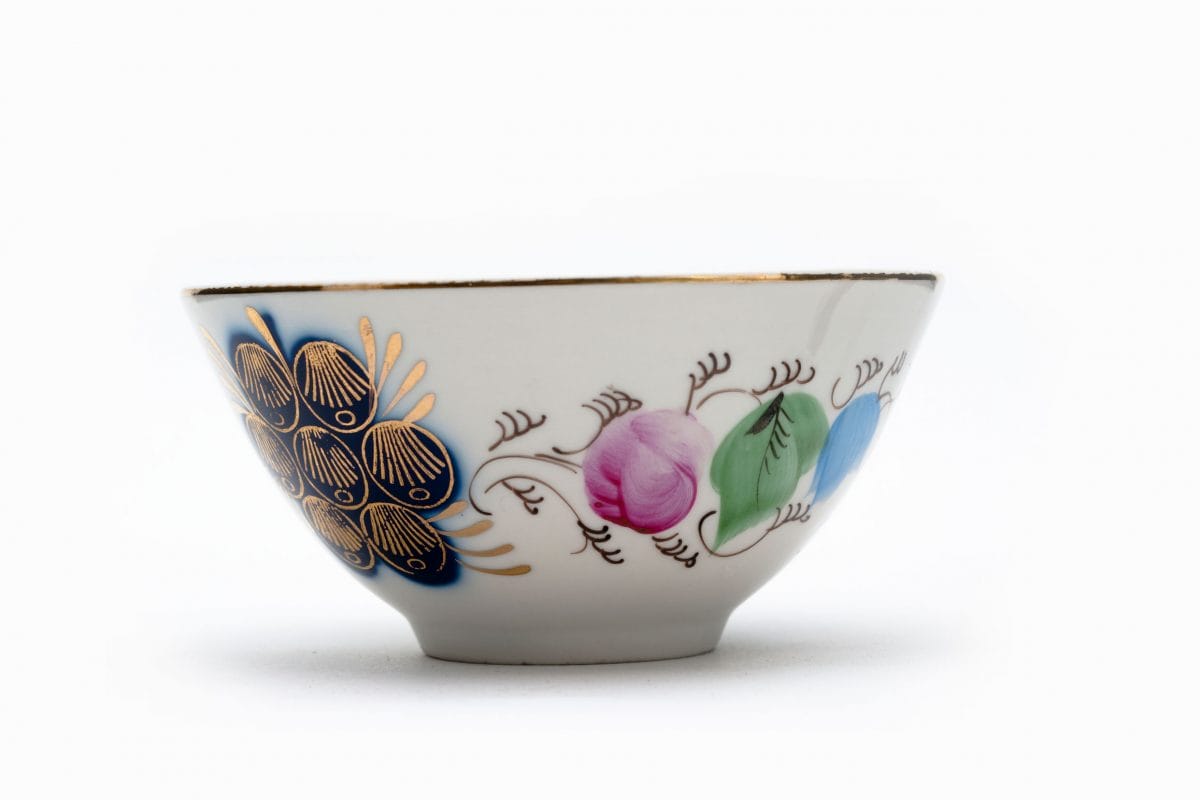 Floral glazed ceramic teacup. White, decorated with blue, pink and green flowers, and embellished with gold.