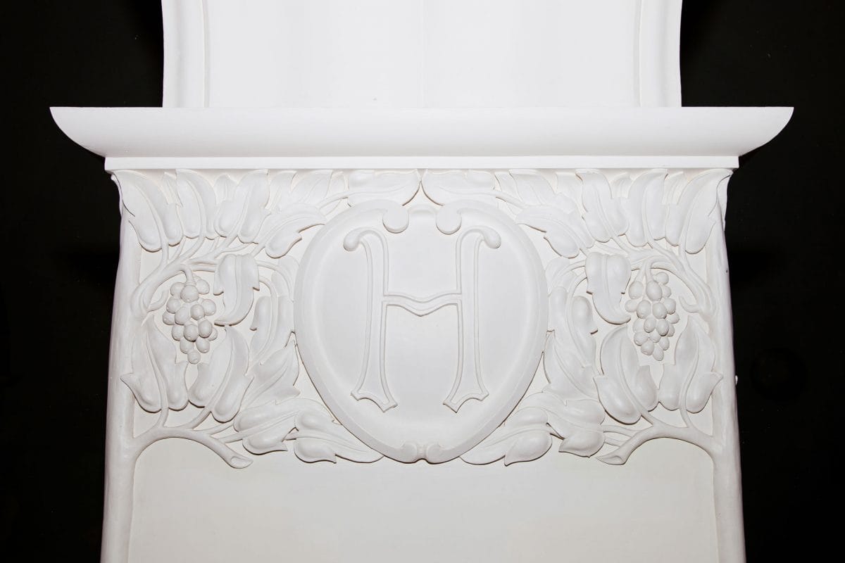 A close up of a white column decorated with white trees and vines