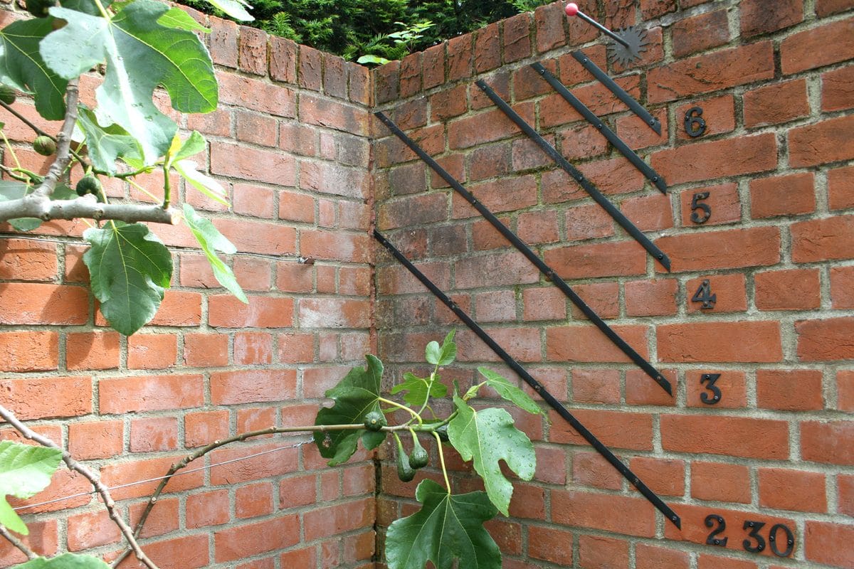 A wall corner with some black lines and numbers, indicating a sundial