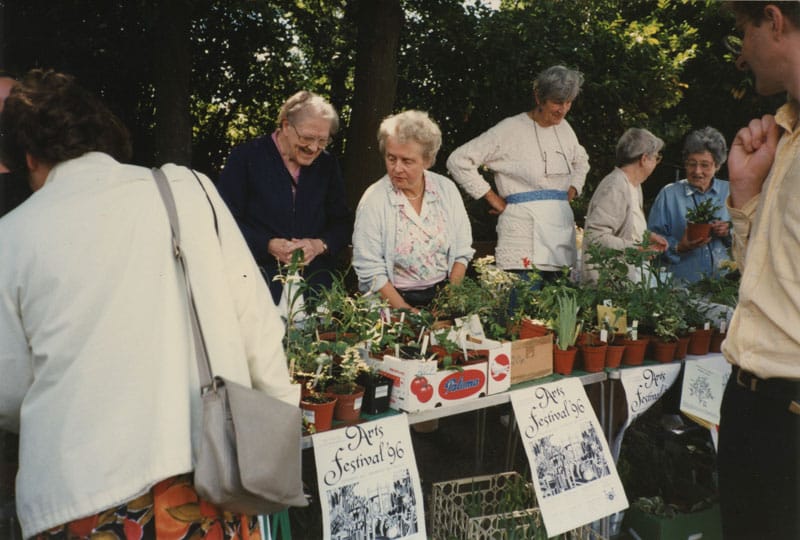 A group of older women selling plants at stall.