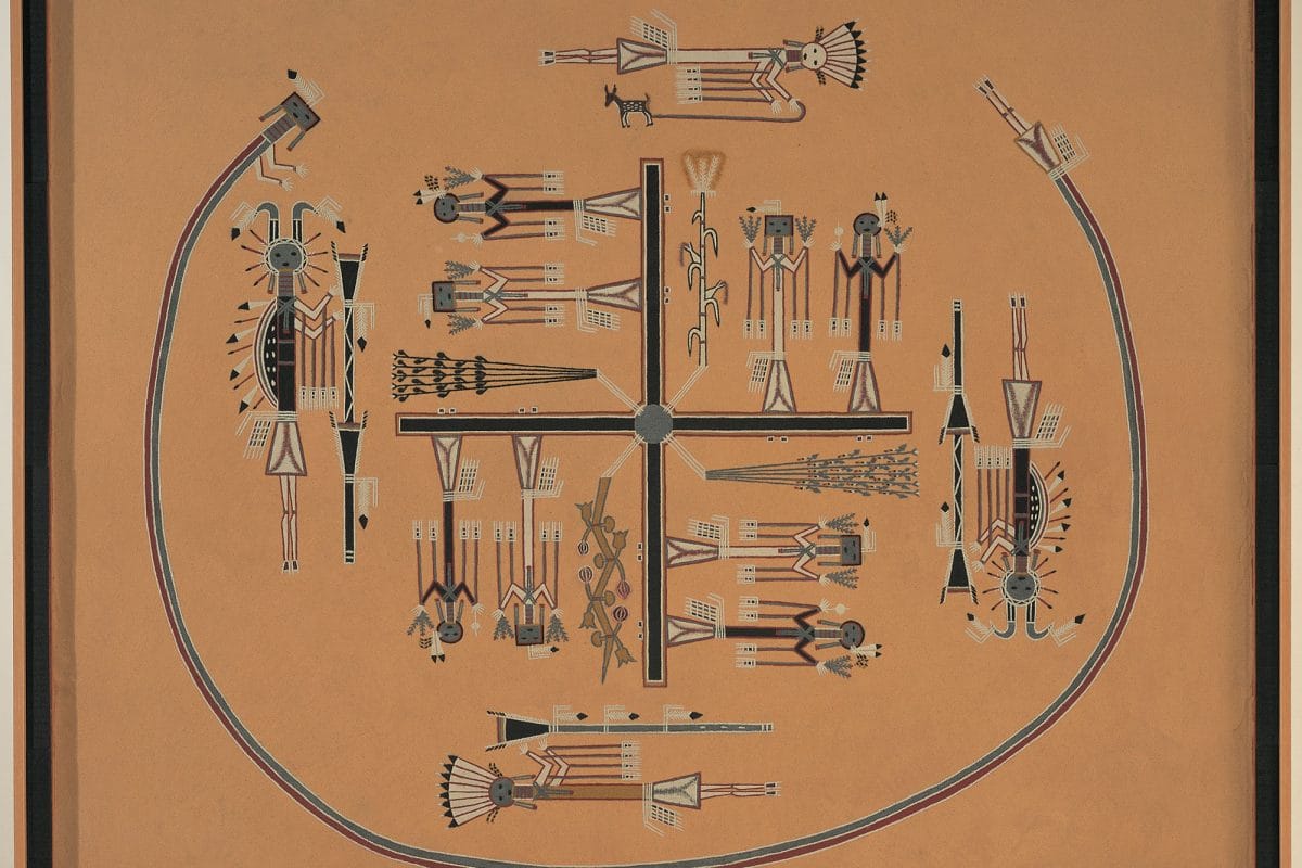 A square painting made of different coloured sands in a wooden frame. There is a dark cross at the centre with figures standing on each arm of the cross with a large open circle around most of the cross and figures