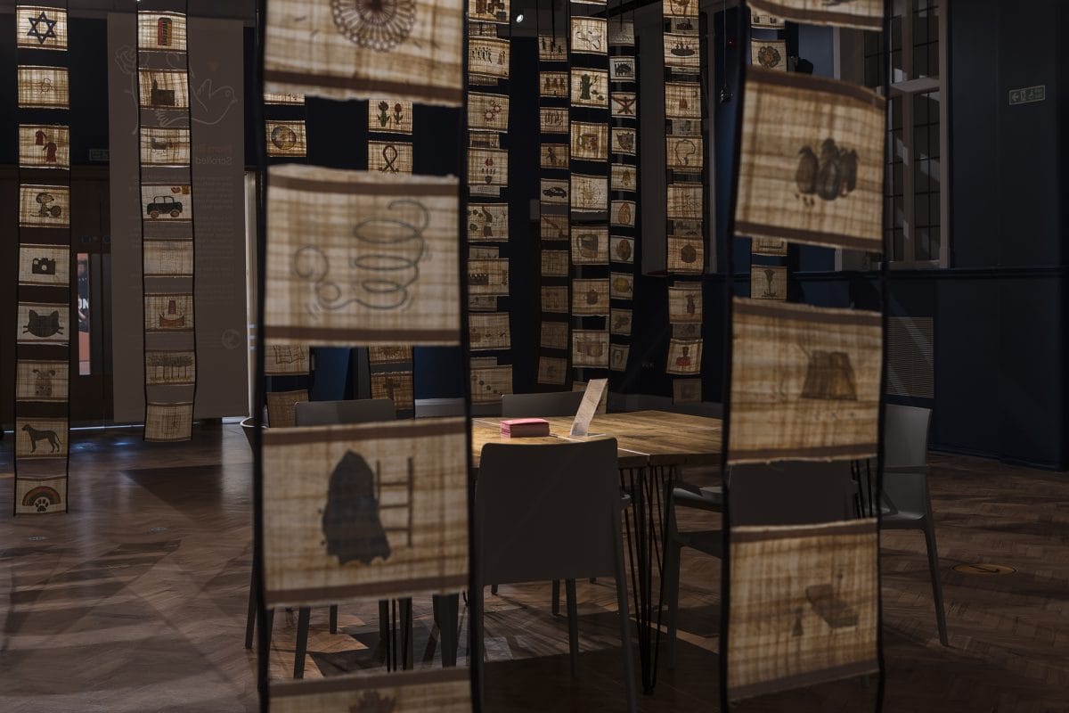 Table in centre of room with scrolls hanging from ceiling