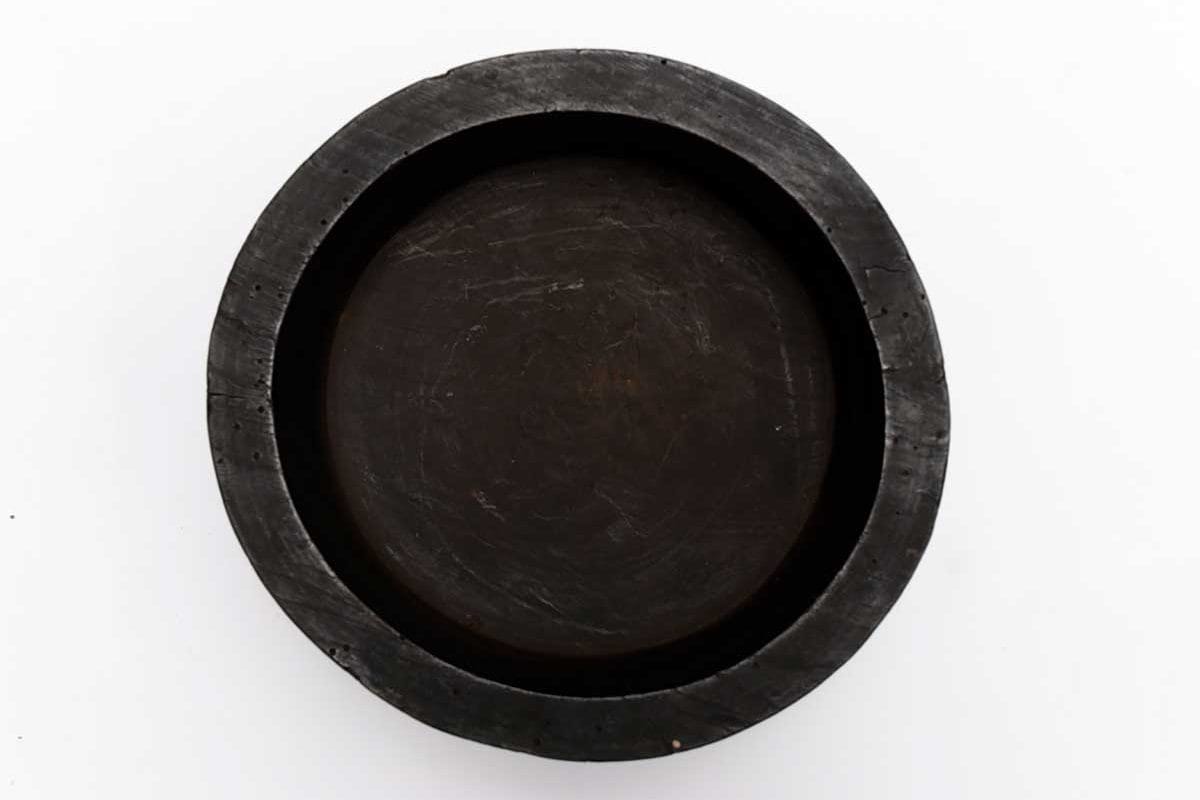 Image shows a black circular mould for cheese