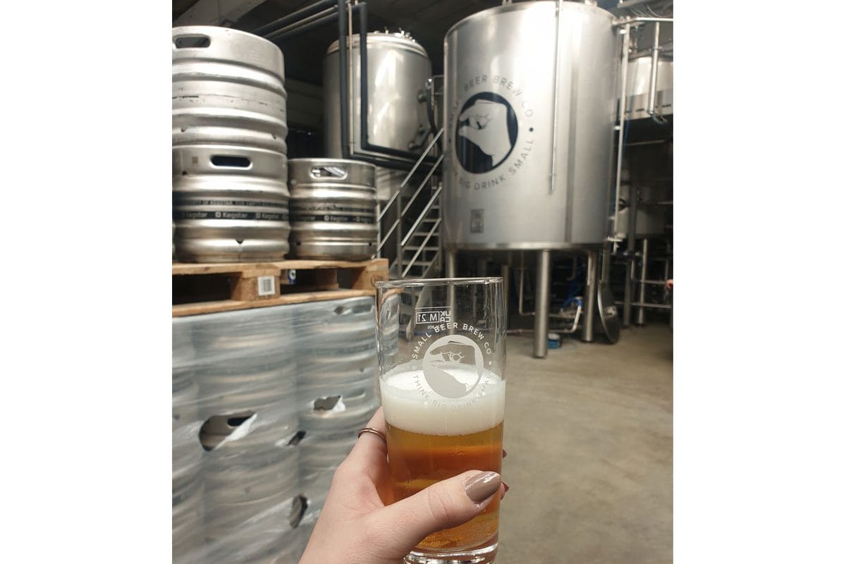 A half filled pint of beer held up in the Small Beer brewery