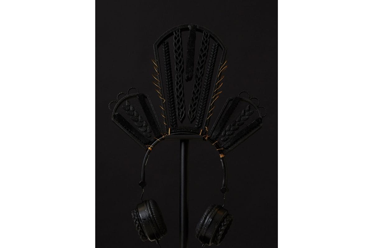 Black headphones with hair woven into three shapes at the top, a taller shape in the middle.