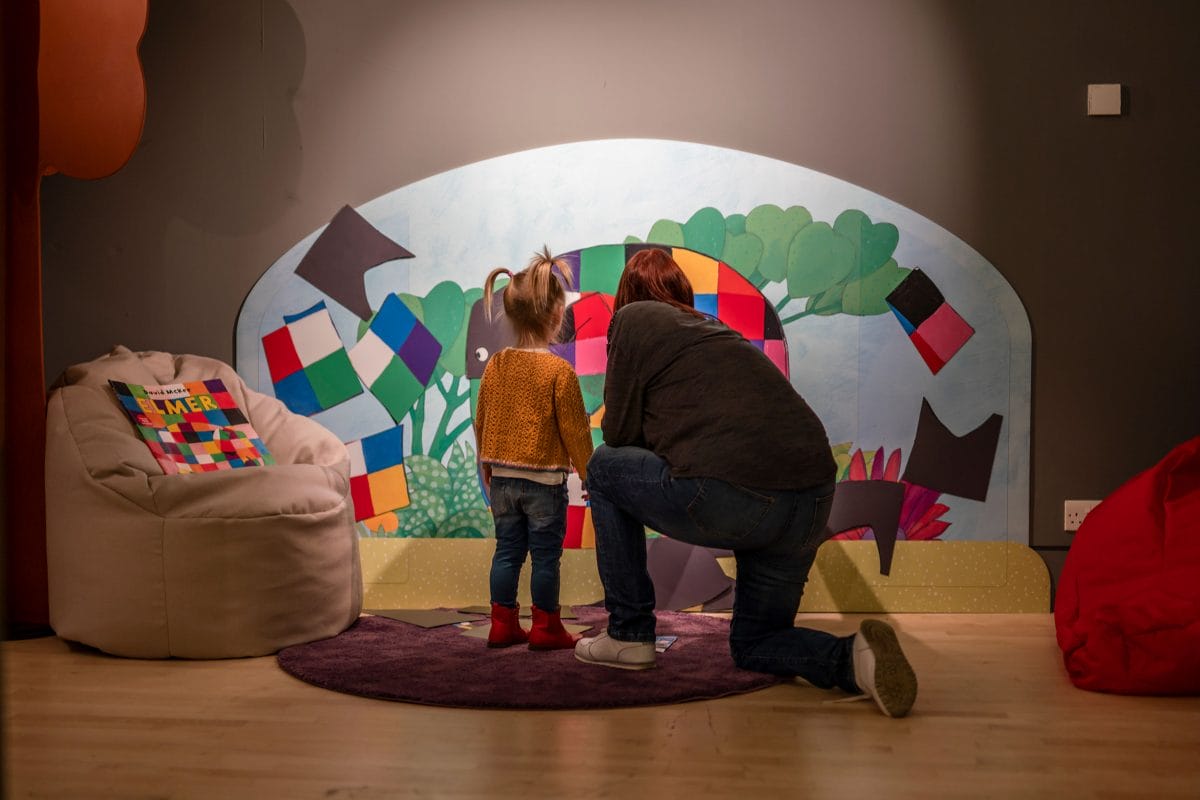 A parent and child looking at an Elmer illustration