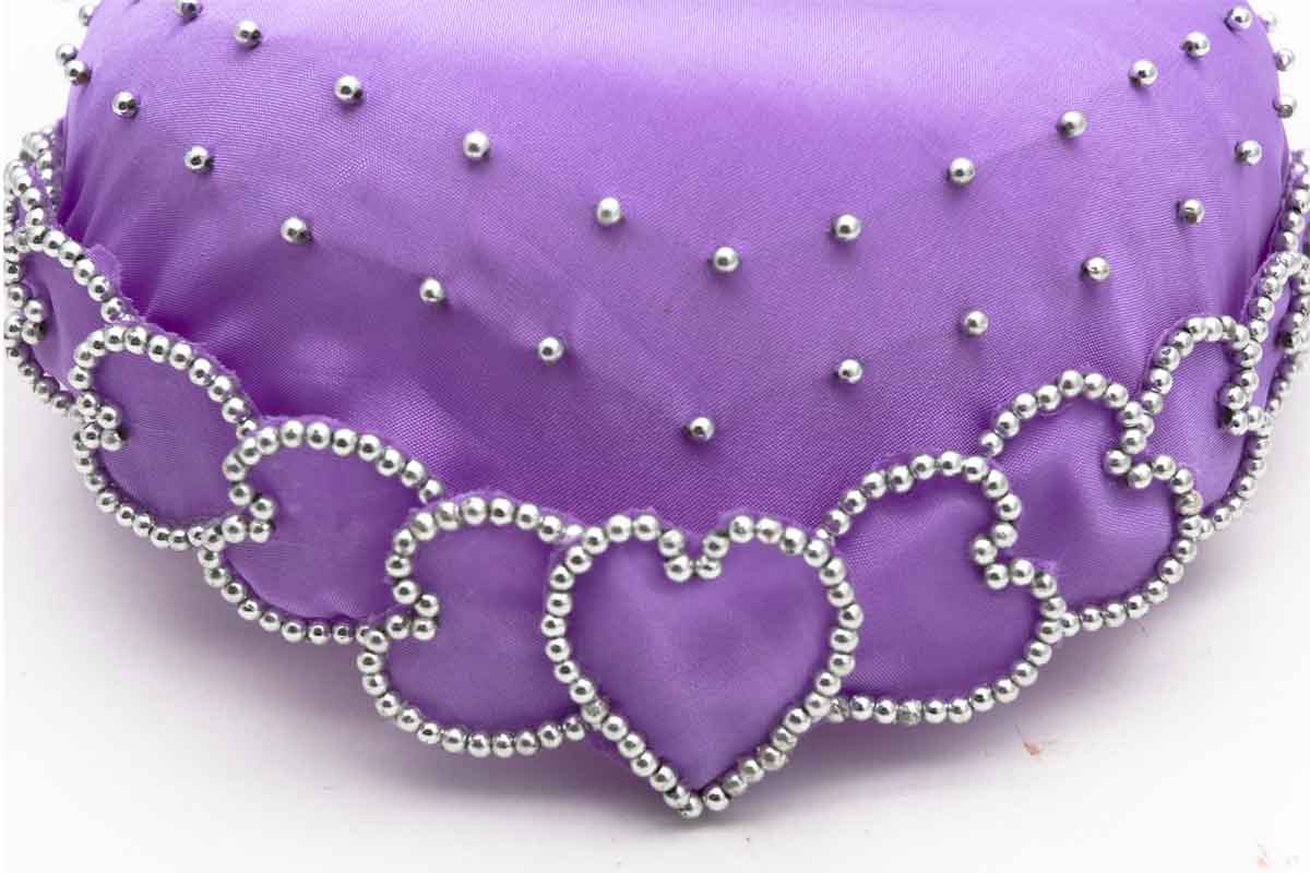 Detail of purple wedding hat with beaded heart pattern