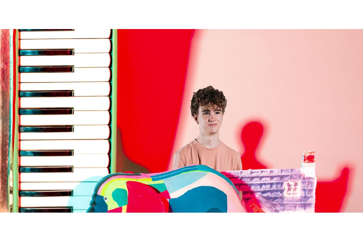 Photo of a young man edited to look small next to a keyboard and colourful elephant