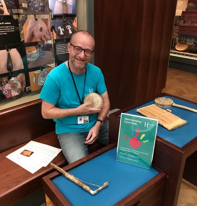 Jon the volunteer at a table holding a talking drum