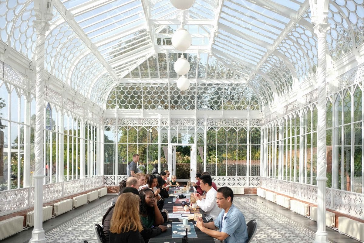 People sat at a long table inside the Horniman Conversatory