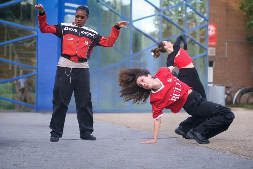 Three young people perform hip-hop dances