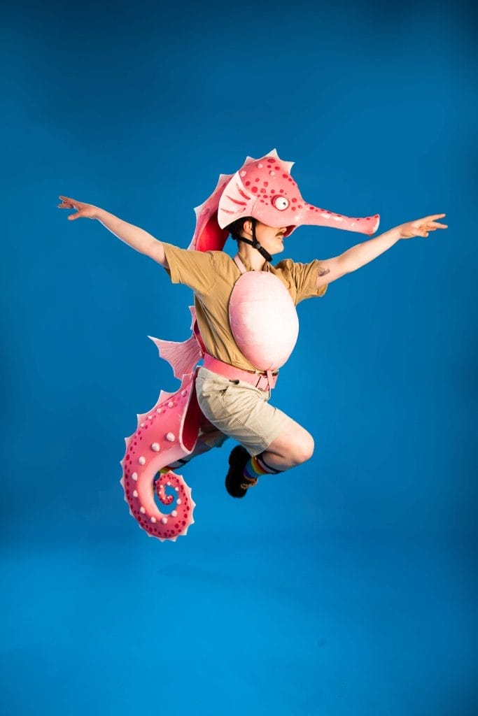 Man leaping in mid air wearing a seahorse head, tail and stomach