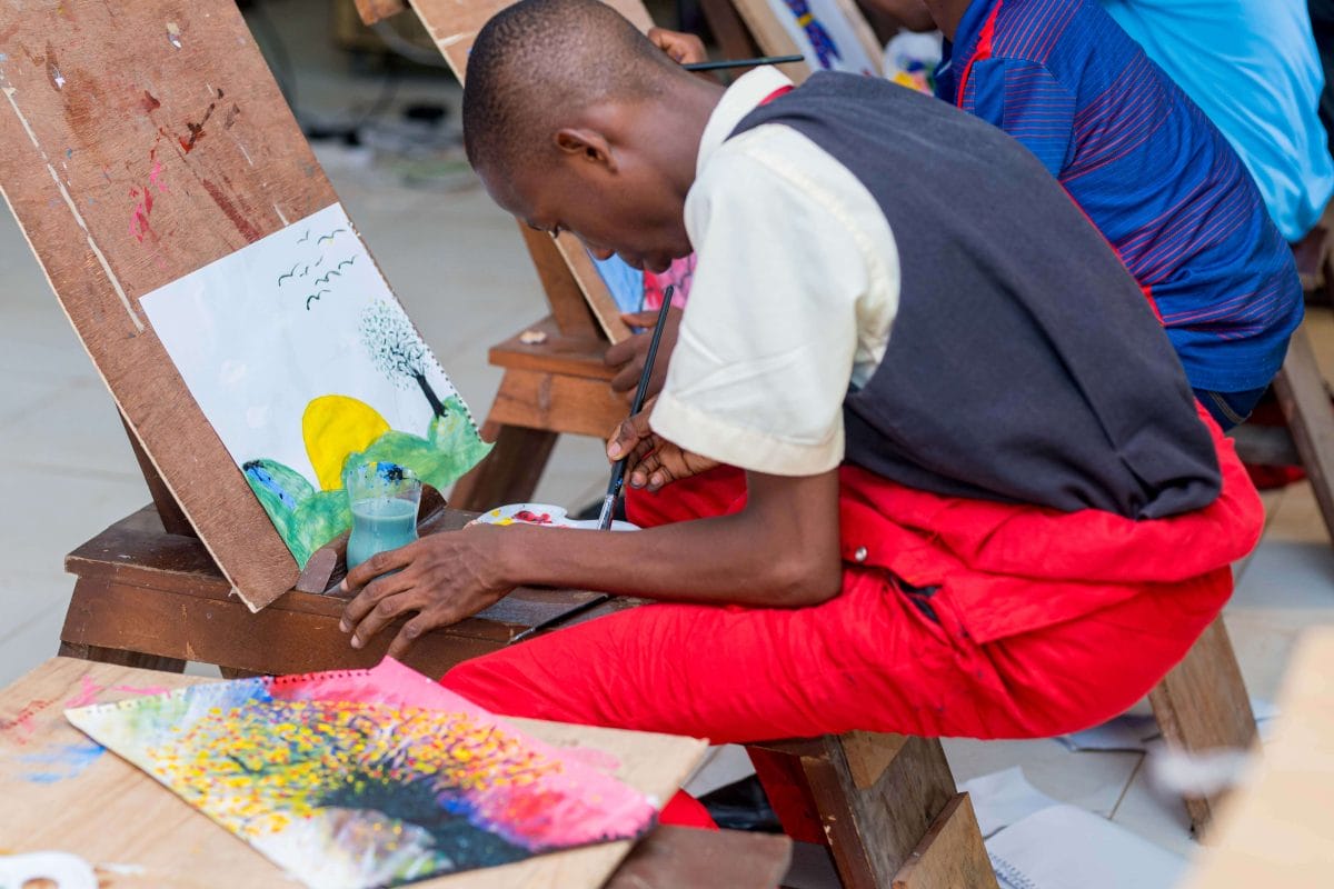 Boy in school uniform does a painting on an easel