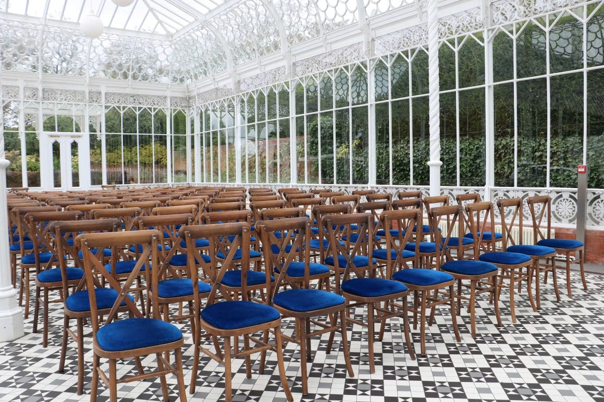 Rows of chairs in the Horniman Conservatory, they are wooden with blue velvet seats