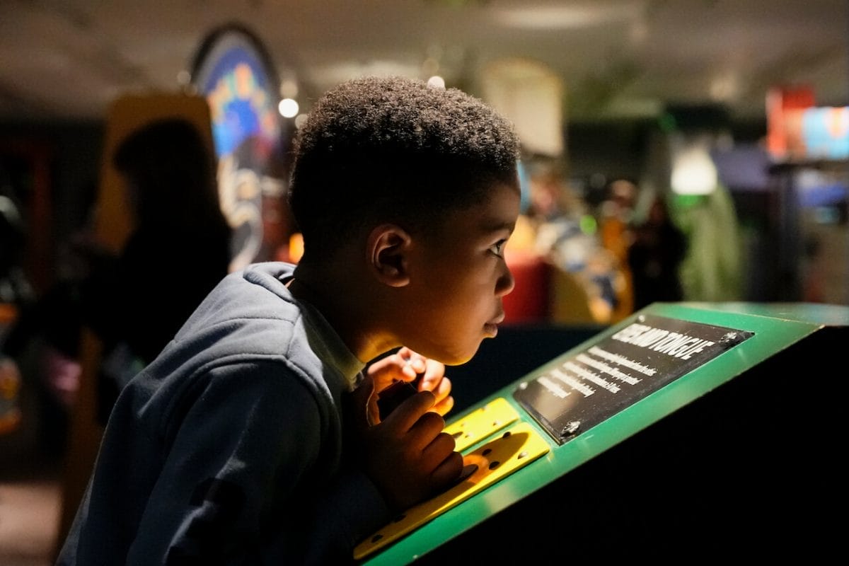 A child leans close as they use a controller