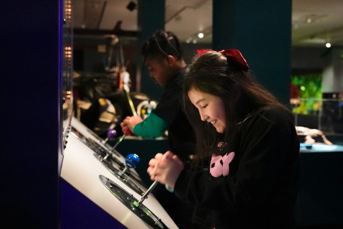 Two children pull on levers on a display case