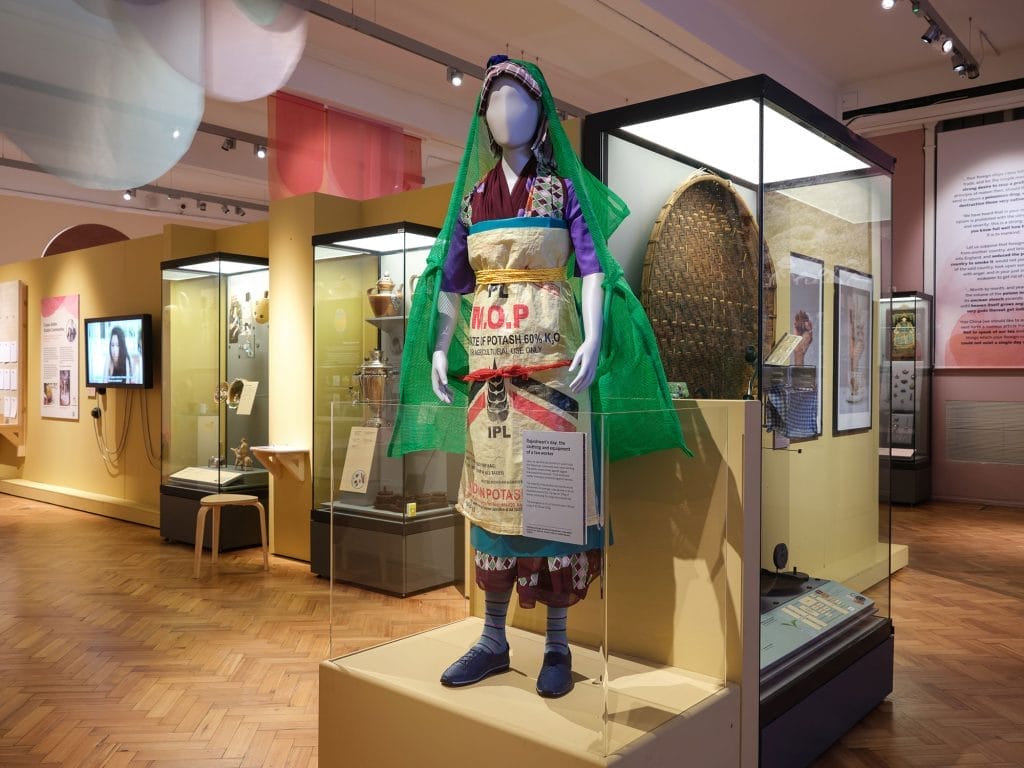 Mannequin wearing tea worker's outfit, a dress made out of a bag tied at the waist and netting over the head