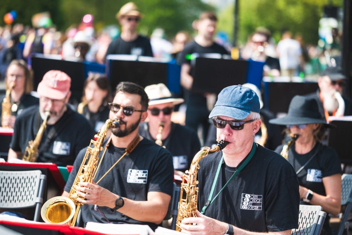 Two men play saxophone as part of a brass band
