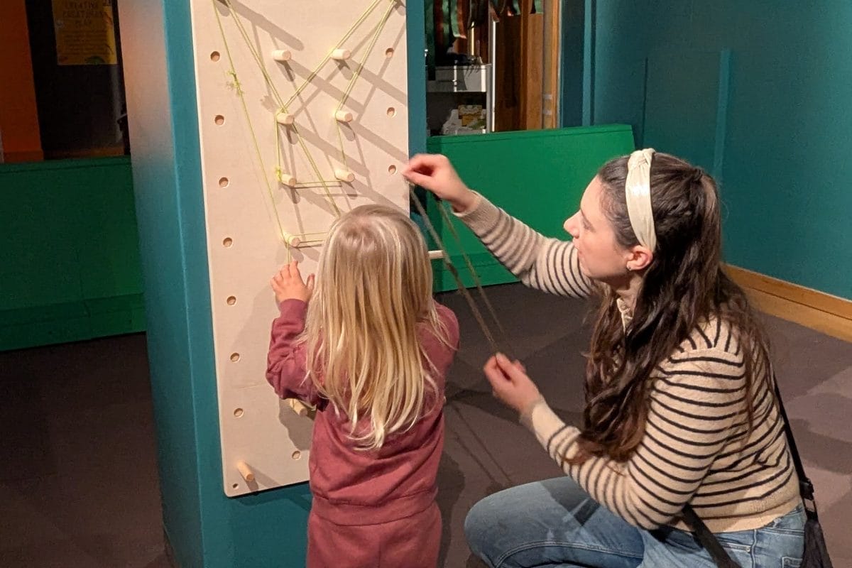 Adult and child loop elastic bands round a pegboard
