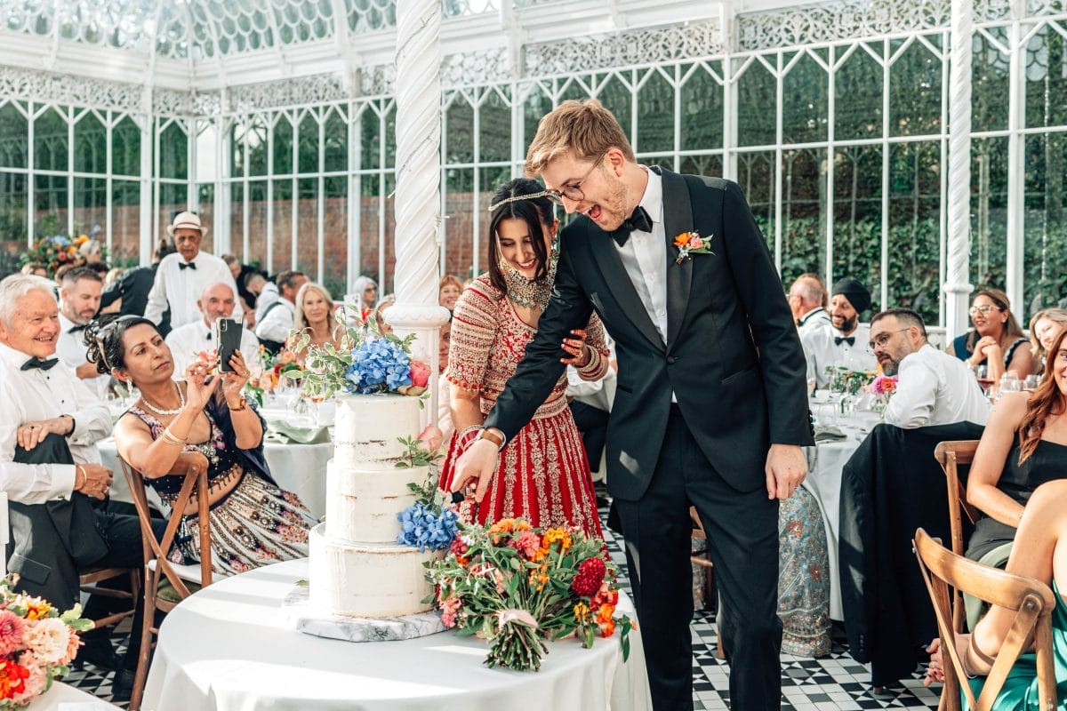 Ravina & Ben cutting cake at their Horniman wedding.