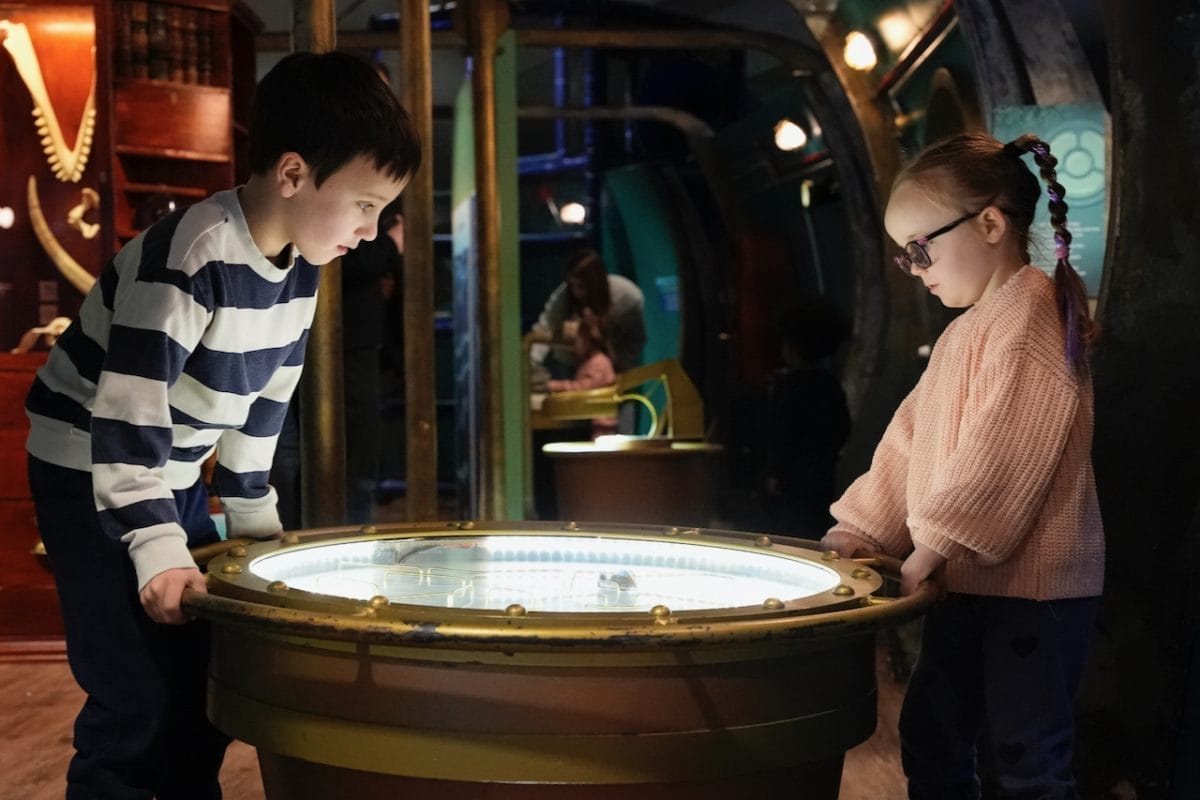 Two children play with an interactive map at the Voyage to the Deep exhibition.