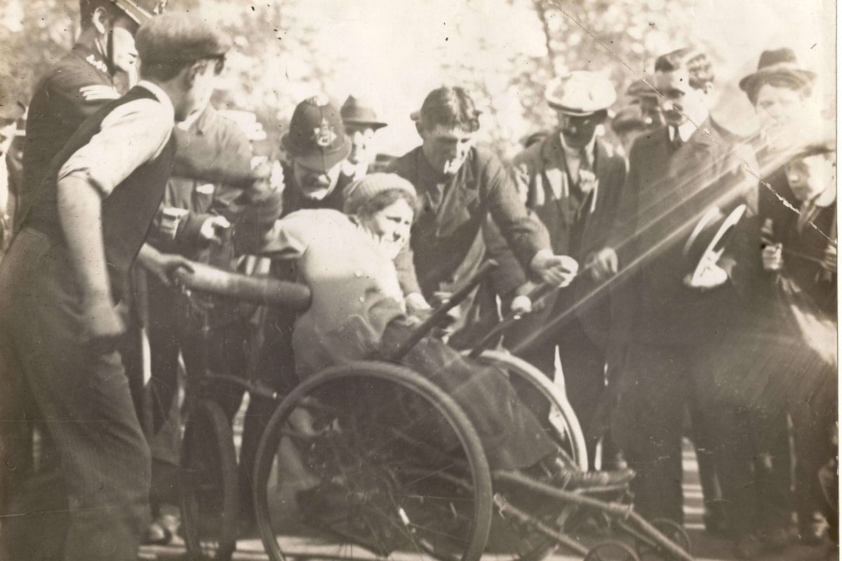 Image of Rosa May Billinghurst in a wheelchair protesting amongst policemen.