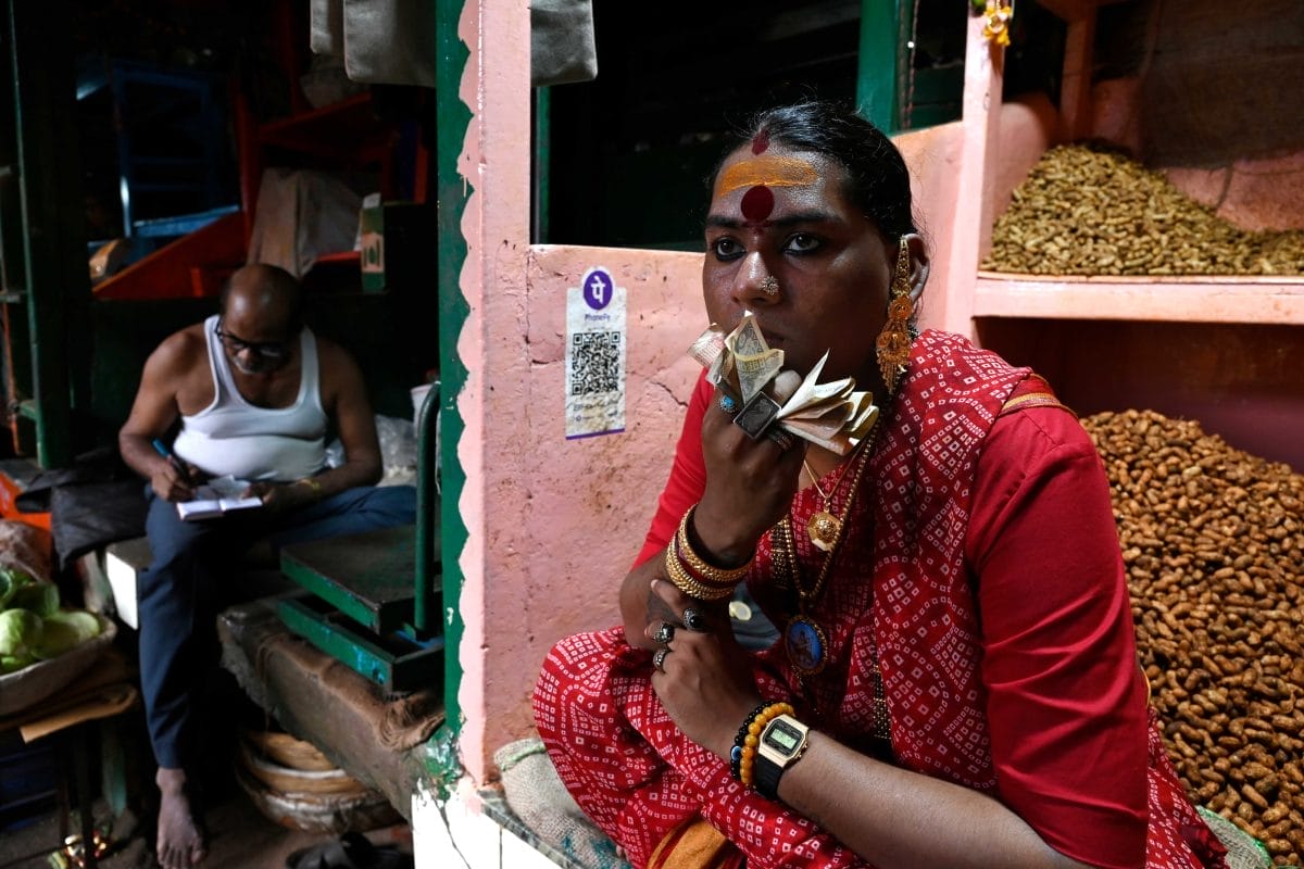Zoya Thomas Lobo, in a market stall, wearing a red sari, holding money