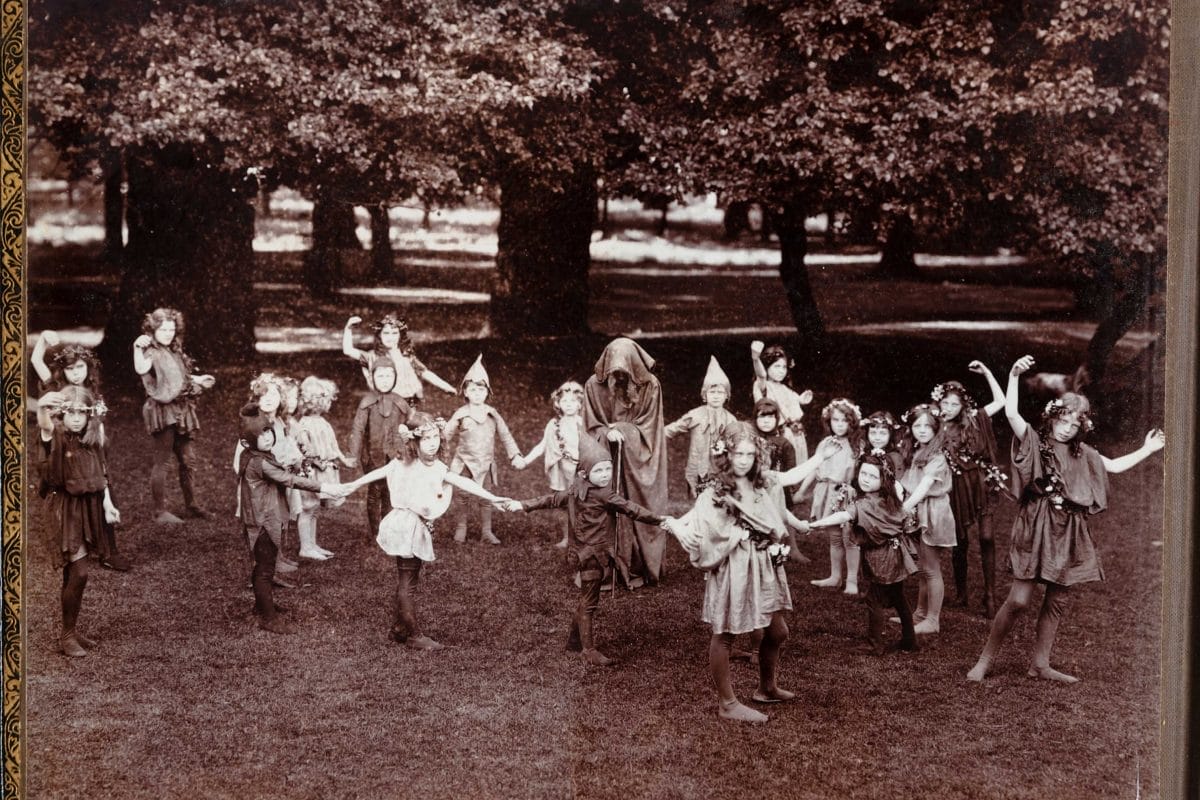 Slide image of children dressed as fairies and standing in a circle by a wood