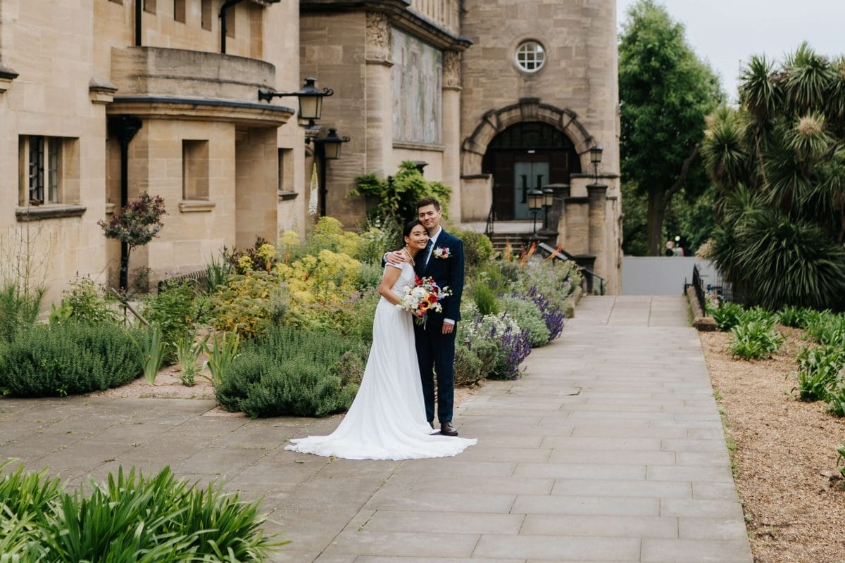 A bride and groom stand in front of the Horniman Clocktower