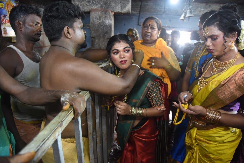 A necklace is put on a woman wearing a sari in a ceremony