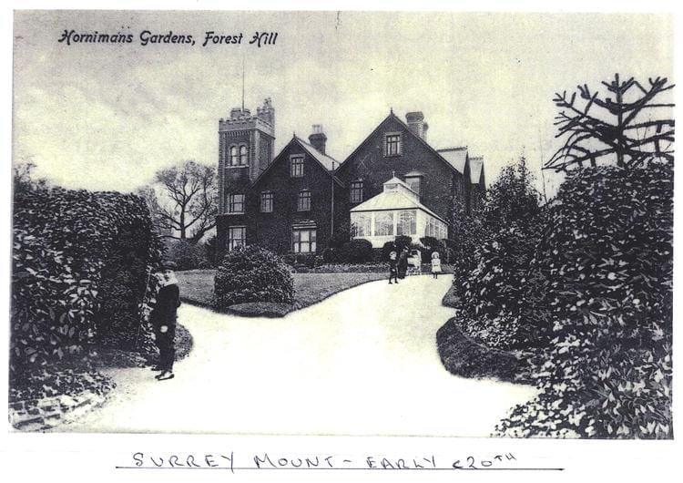 A postcard showing a photo in black and white of a large house with a turret and a conservatory. two boys are in the photo closer to the camera