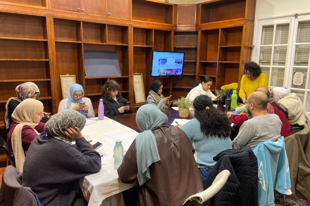 People sat round a table looking at individual work and a screen at a workshop
