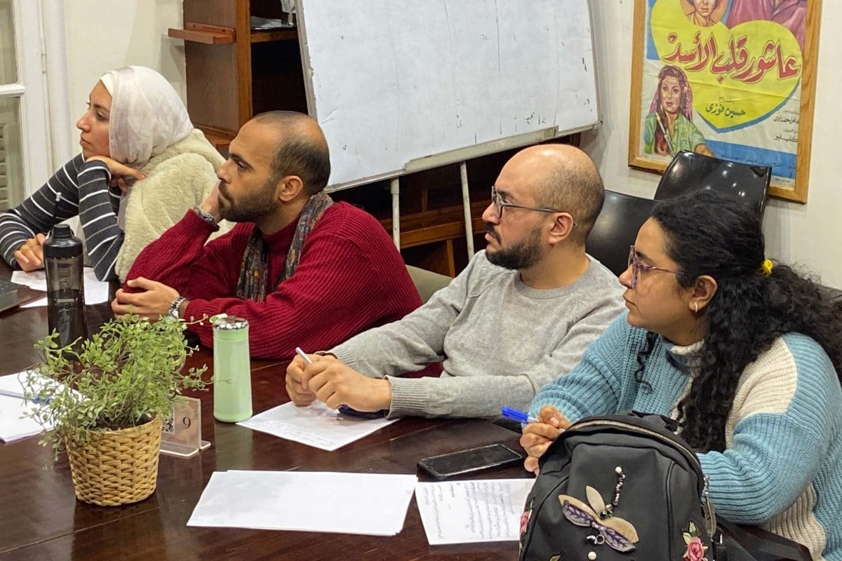 Four people sat at a table in a workshop